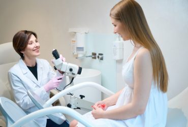 Gynecologist uses a gynecological microscope in her work, the young patient is located in a gynecological chair for examination